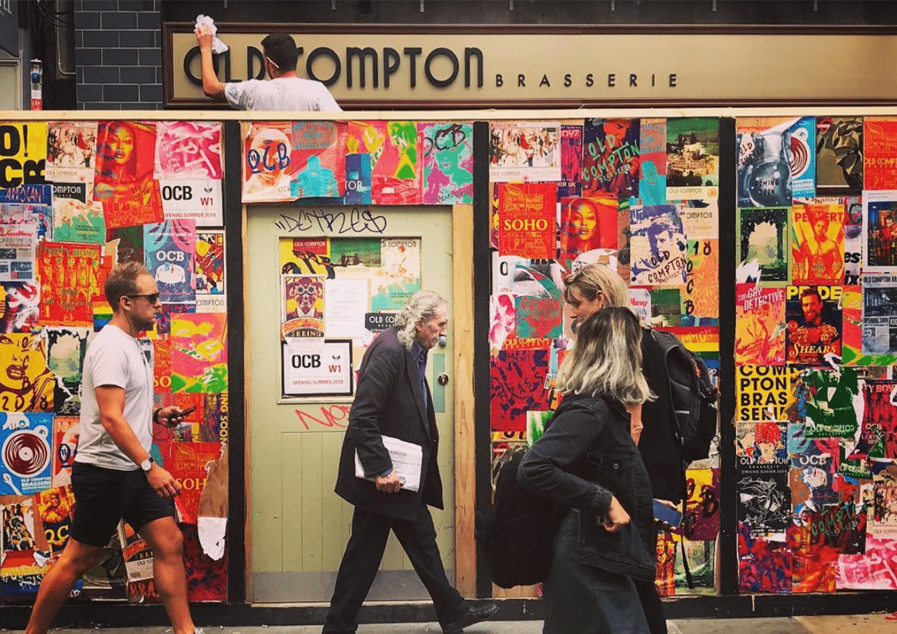 Old Compton Brasserie - Hoarding design and facade design showing the logo on the venue front, as well as the colourful posters surrounding the wooden construction hoarding.